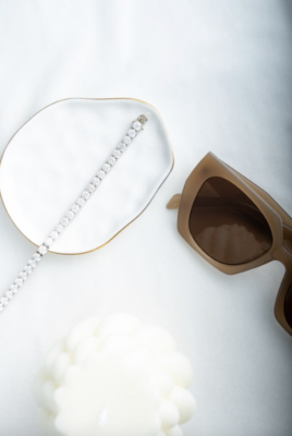 A tennis bracelet in a styled shot along with a pair of sunglasses and a candle.